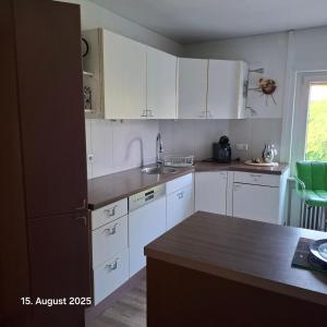 a kitchen with white cabinets and a black refrigerator at Casa Calali haustierfreundlich u barrierefrei in Bad Endbach