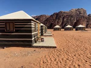 a row of huts in the desert with a mountain at Starry Nights Luxury Camp in Wadi Rum