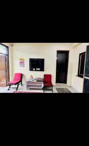 a living room with two red chairs and a couch at Green tree house in Dharmsāla