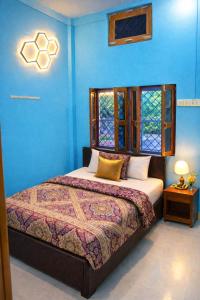 a bedroom with a bed with blue walls and a window at Ma vindhyavasini Atithi Bhavan in Naimishāranya