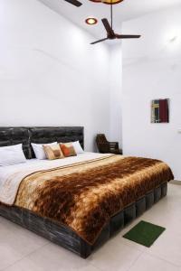a bedroom with a large bed with a brown blanket at Ma vindhyavasini Atithi Bhavan in Naimishāranya +12 photos