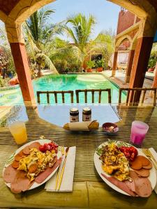 een tafel met twee borden eten en een zwembad bij Téranga paradis in Somone
