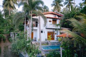 a house with a swimming pool and palm trees at Brown Birds Villa in Tangalle