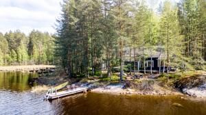 a house on the shore of a lake with a dock at Mökki Aapola in Puumala