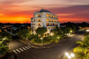 a white building on a street with a sunset at JM Hoi An Beach Hotel - Free Shuttle Car To Old Town in Hoi An