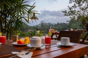 a wooden table with plates of food and drinks on it at Namara Green Ella in Ella