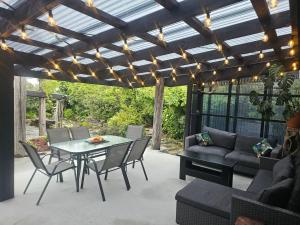 a patio with a table and chairs and a couch at Livingstone Retreat in Hokitika