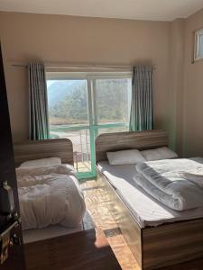 two beds in a room with a large window at Gauthali Inn in Netadurling