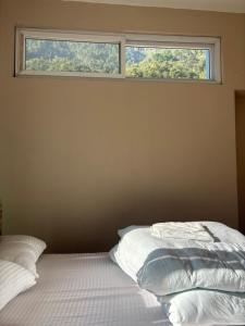 a bedroom with a bed with two pillows and a window at Gauthali Inn in Netadurling +3 photos