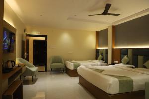a hotel room with two beds and a ceiling fan at Hotel N Grand in Miriālgūda