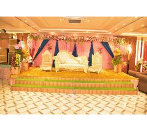 a stage with two white chairs and a couch at The Kuber Hotel in Bareilly