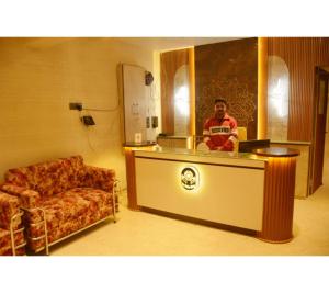a man sitting at a counter in a room with a couch at The Kuber Hotel in Bareilly