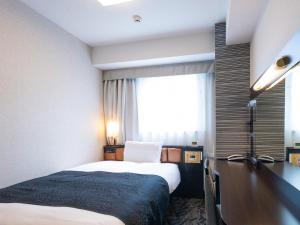 a hotel room with a bed and a desk and a window at APA Hotel Nagoya Ekimae in Nagoya
