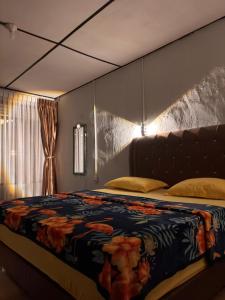 a bedroom with a large bed with a blanket at Bungalow Karo Hill in Berastagi
