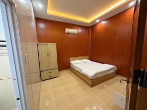 a small room with a bed and a refrigerator at Motel Anh Khoa in Tam Kỳ