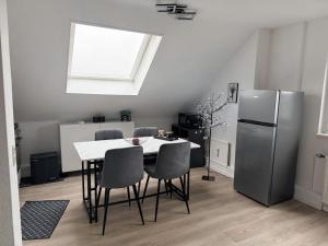 a kitchen with a table with chairs and a refrigerator at Gemütliche Wohnung über den Dächern von Gevelsberg in Gevelsberg