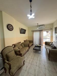 a living room with couches and a clock on the wall at Seaview horizon apartment in Sowayma