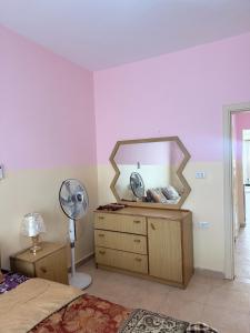 a bedroom with a mirror and a dresser with a fan at Seaview horizon apartment in Sowayma +2 photos