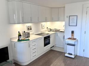 a white kitchen with white cabinets and a refrigerator at Regatta - A lakeview apartment in Thorpeness - Aldeburgh Coastal Cottages in Thorpeness +18 photos