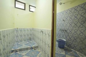 a bathroom with a tiled floor with a bucket in it at Ashu Homestay Nest 1 in Pondicherry