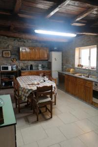 a kitchen with a table and a refrigerator in it at Nature House Lagos do Sabor in Torre de Moncorvo