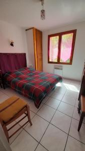 a bedroom with a bed and a chair and two windows at Rez de Jardin Guillestre in Guillestre