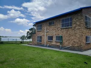 a brick building with a lawn in front of it at Vaaldamhuis in Oranjeville