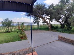 an umbrella in a patio with a view of the water at Vaaldamhuis in Oranjeville