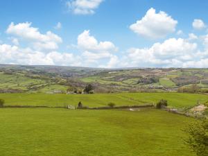 a field of green grass with a blue sky and clouds at Fairhead Cottage in Grosmont
