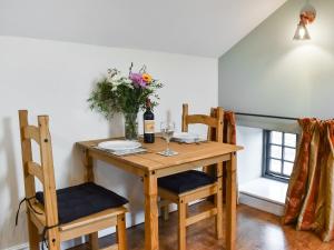 a dining room table with two chairs and a vase of flowers at Fairhead Cottage in Grosmont +8 photos