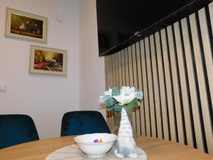 a vase of flowers on a table with a bowl at Aurora Lux in Vrnjačka Banja