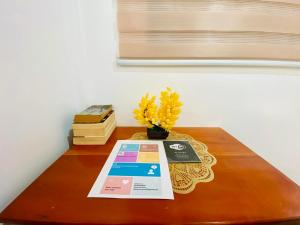 a table with a book and a vase with yellow flowers at Emmanuel2A Homestay in San Vicente