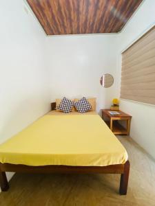 a bedroom with a bed with a yellow sheet on it at Emmanuel2A Homestay in San Vicente