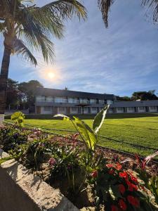 a building with a palm tree and some flowers at Castelo do Lago Hotel e Restaurante in Fama