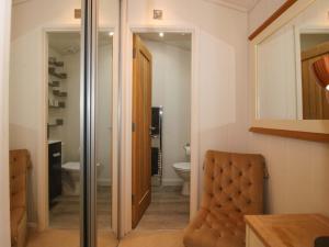 a bathroom with a chair and a toilet in it at The Hedgerows - Hillview Lodges in Kidderminster +28 photos