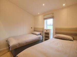 two beds in a small room with a window at The Hedgerows - Hillview Lodges in Kidderminster