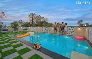 a group of people standing on a fence near a swimming pool at EKOSTAY - Alpine Villa in Alibaug