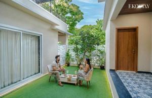 a man and a woman sitting on the patio of a house at EKOSTAY - Alpine Villa in Alibaug