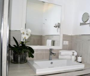 ein weißes Badezimmer mit Waschbecken und Spiegel in der Unterkunft Arneo Terra del Sole B&B in Torre Lapillo