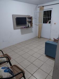 a living room with a television and a tiled floor at Casa Praça in Paripueira