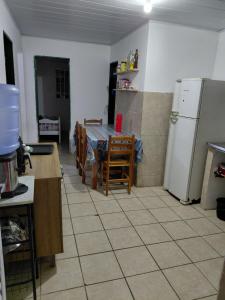 a kitchen with a table and a white refrigerator at Casa Praça in Paripueira