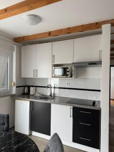 a kitchen with white cabinets and a black counter top at Apartman Lapaž 12 in Toplice Sveti Martin