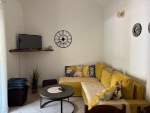 a living room with a yellow couch and a table at Apartmani Kežić Drvenik in Drvenik
