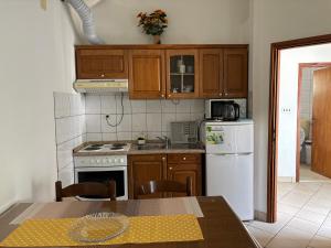a kitchen with wooden cabinets and a table and a refrigerator at Apartmani Kežić Drvenik in Drvenik