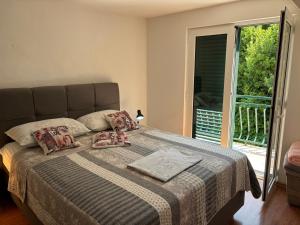 a bedroom with a bed with pillows and a balcony at Apartmani Kežić Drvenik in Drvenik