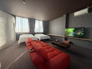 a living room with a red couch and a tv at 欒裏町ouchi uramachi in Matsumoto