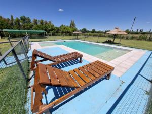 a swimming pool with two benches and an umbrella at Complejo Balcarce in San Rafael +4 photos