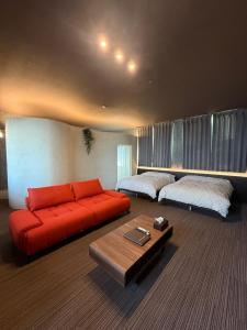 a living room with a red couch and two beds at 欒裏町ouchi uramachi in Matsumoto