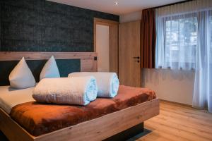una camera con letto in legno e cuscini bianchi di die Harmonie a Nauders