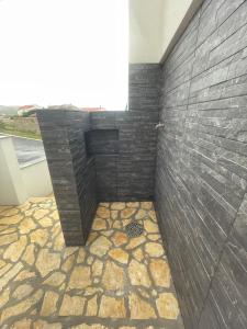 a bathroom with a shower with a black brick wall at Second home apartment - gold in Kustići